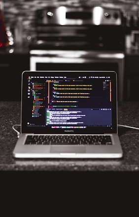 A developer coding on a laptop with design sketches and restaurant order screens around.