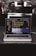 A laptop is placed on a dark granite surface. The screen displays coding software with lines of colorful code. The background features a modern kitchen with a blurred stovetop and backsplash.