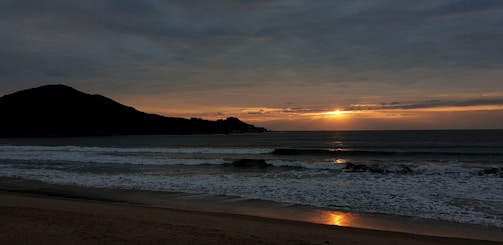 A serene coastal scene at sunset with soft blush and gold tones reflecting on gentle waves.