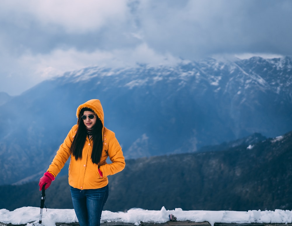 woman in orange hoodie standing near mountain