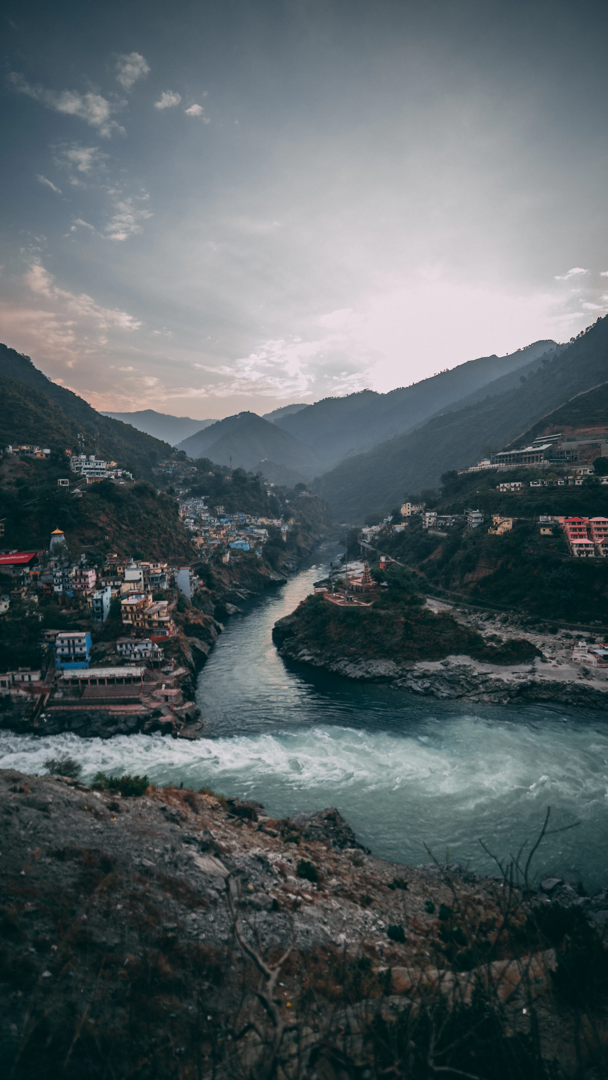 River confluence between steep hills and a small town, Uttarakhand