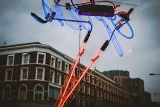 A vibrant blue and yellow pole sign glowing brightly against an evening sky on a busy city street.