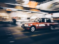 A social media style video thumbnail featuring a dynamic shot of a car in motion on a city street.