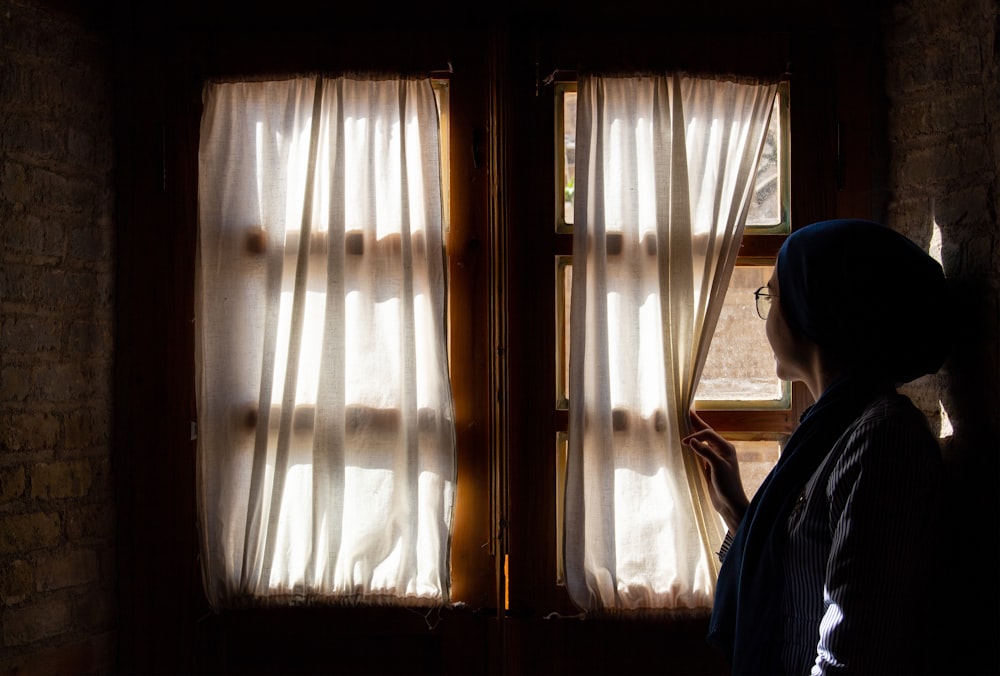 Mujer sosteniendo la cortina de la ventana