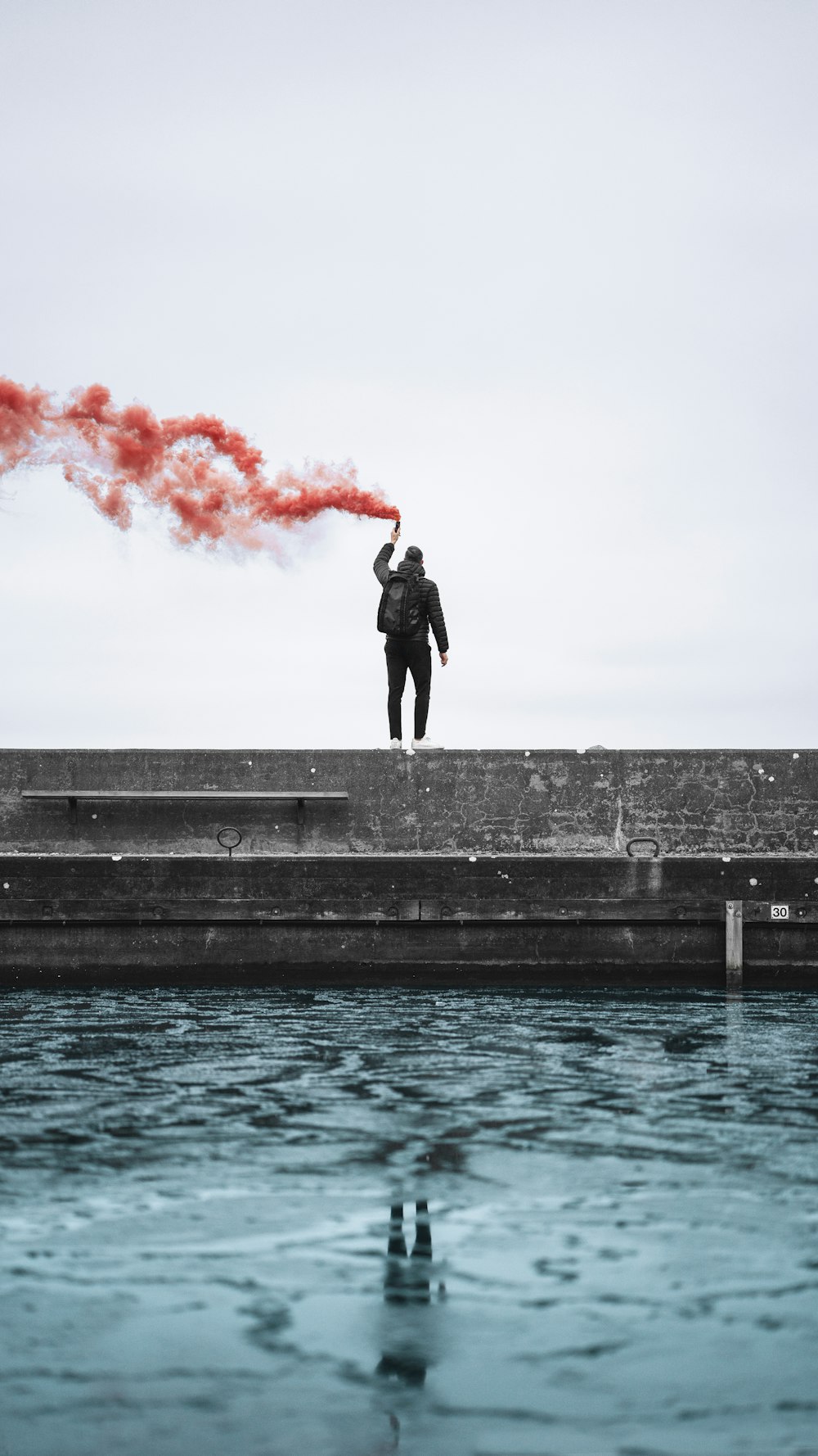 standing man holding lighted flare during daytime