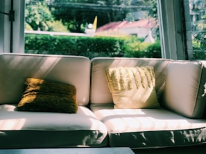 A freshly cleaned white sofa glowing under natural light with a Luxembourg flag-themed pillow.