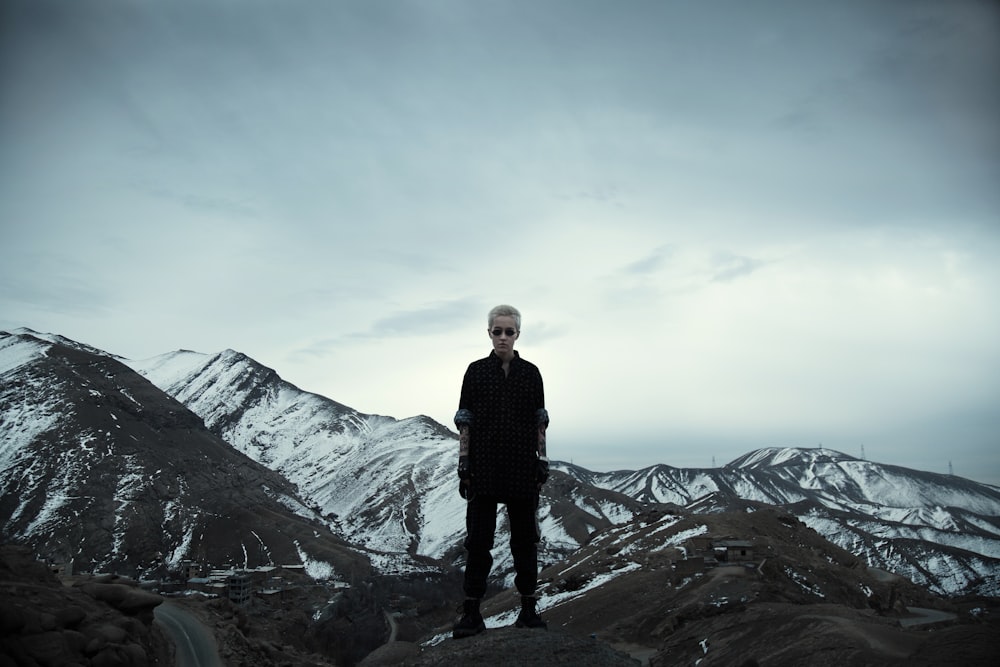 man in black jacket standing on top of mountain