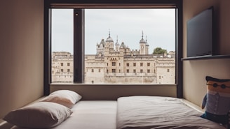 Modern hotel room with minimalist decor and a large window overlooking Spøttrup Castle.