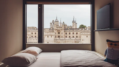 Elegant bedroom featuring minimalist design, plush bedding, and a panoramic view of the city.