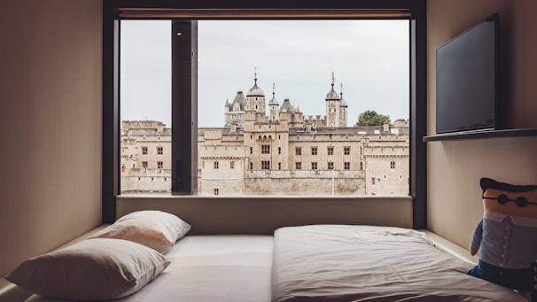 Modern hotel room with minimalist decor and a large window overlooking Spøttrup Castle.