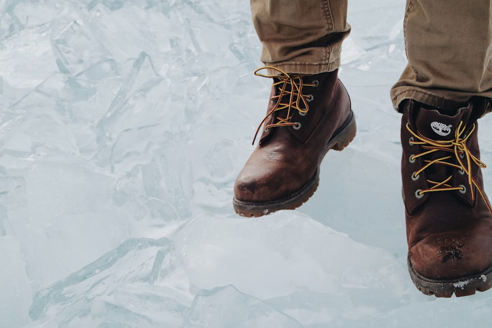 Persona con botas marrones caminando sobre suelo nevado
