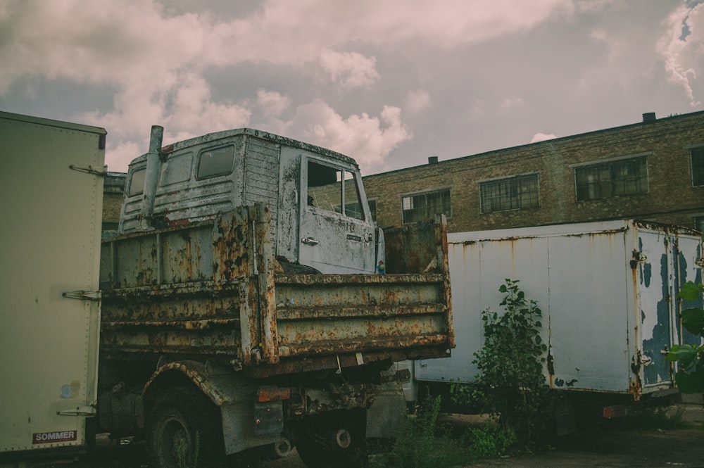 two rust trucks park near building