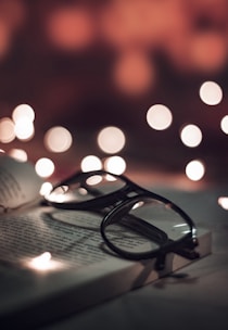selective photo of black-framed eyeglasses on opened book