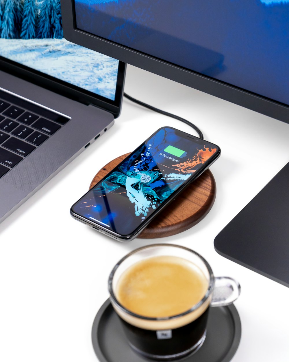 clear glass teacup on table beside phone and laptop