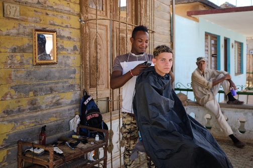 A father and son getting haircuts together in a mobile barbershop.