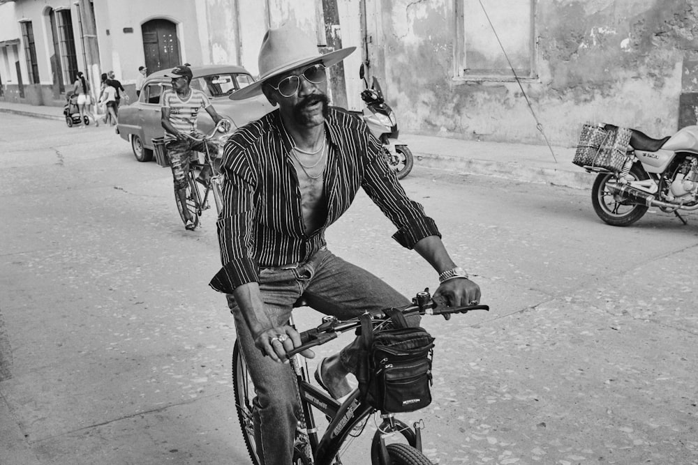 grayscale photo of man riding bicycle outside during daytime