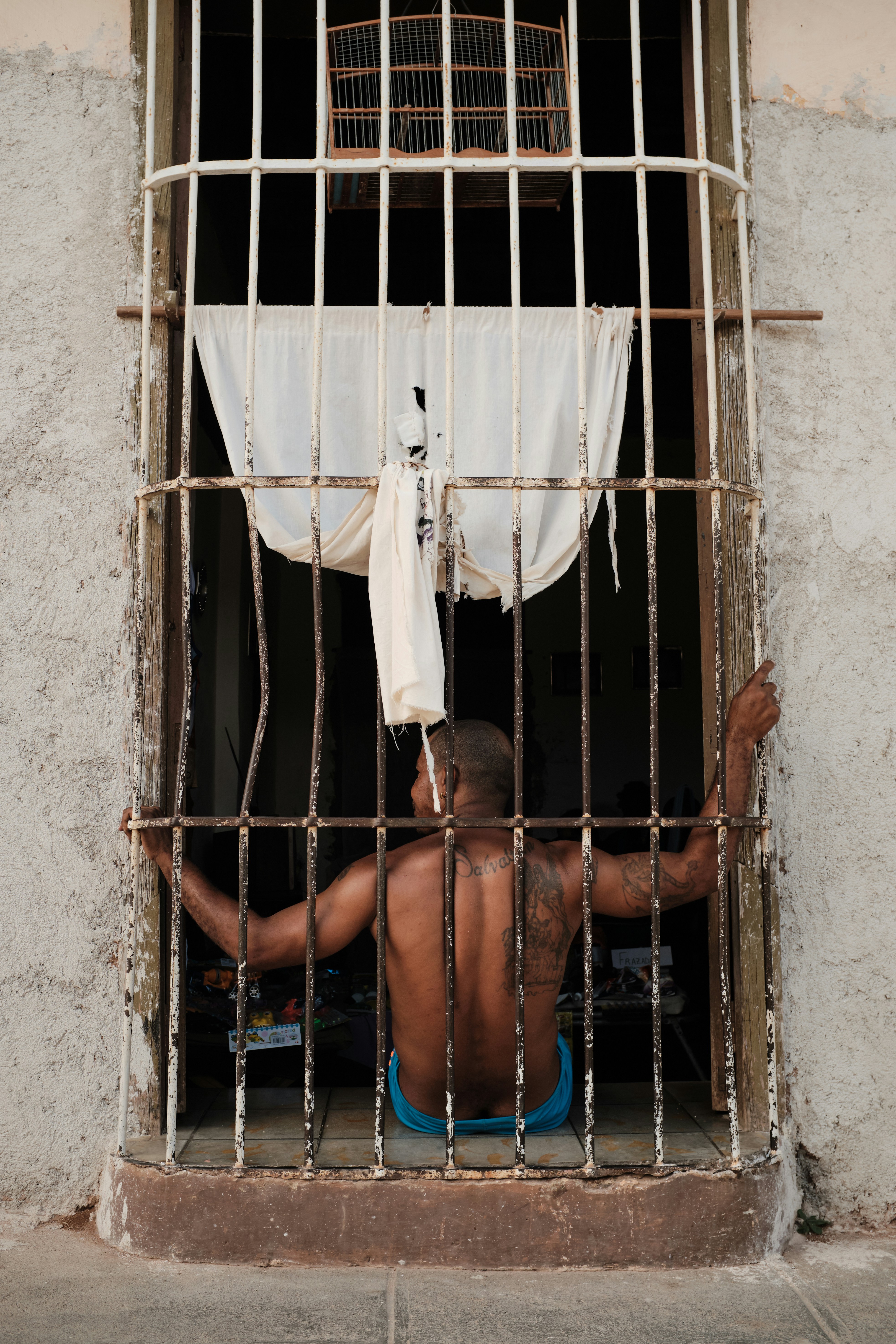 topless sitting behind metal grill