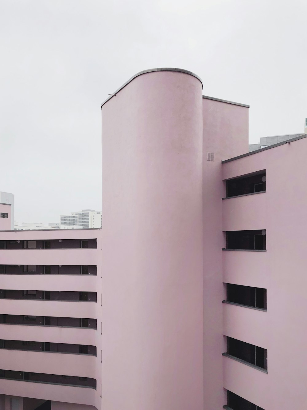 낮에 회색 하늘 아래 분홍색 콘크리트 건물