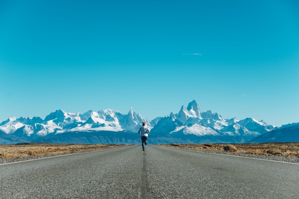 An image of a lone runner on a paved road in Patagonia