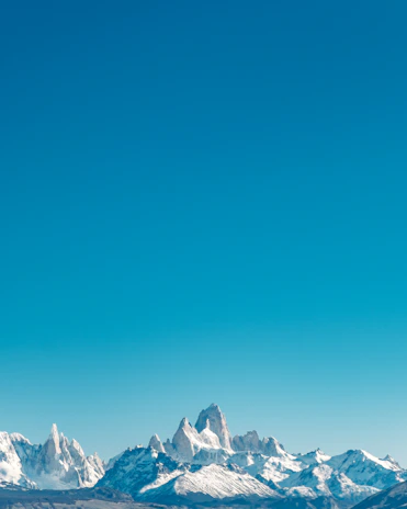A sweeping aerial view of a rugged mountain range under a clear blue sky.