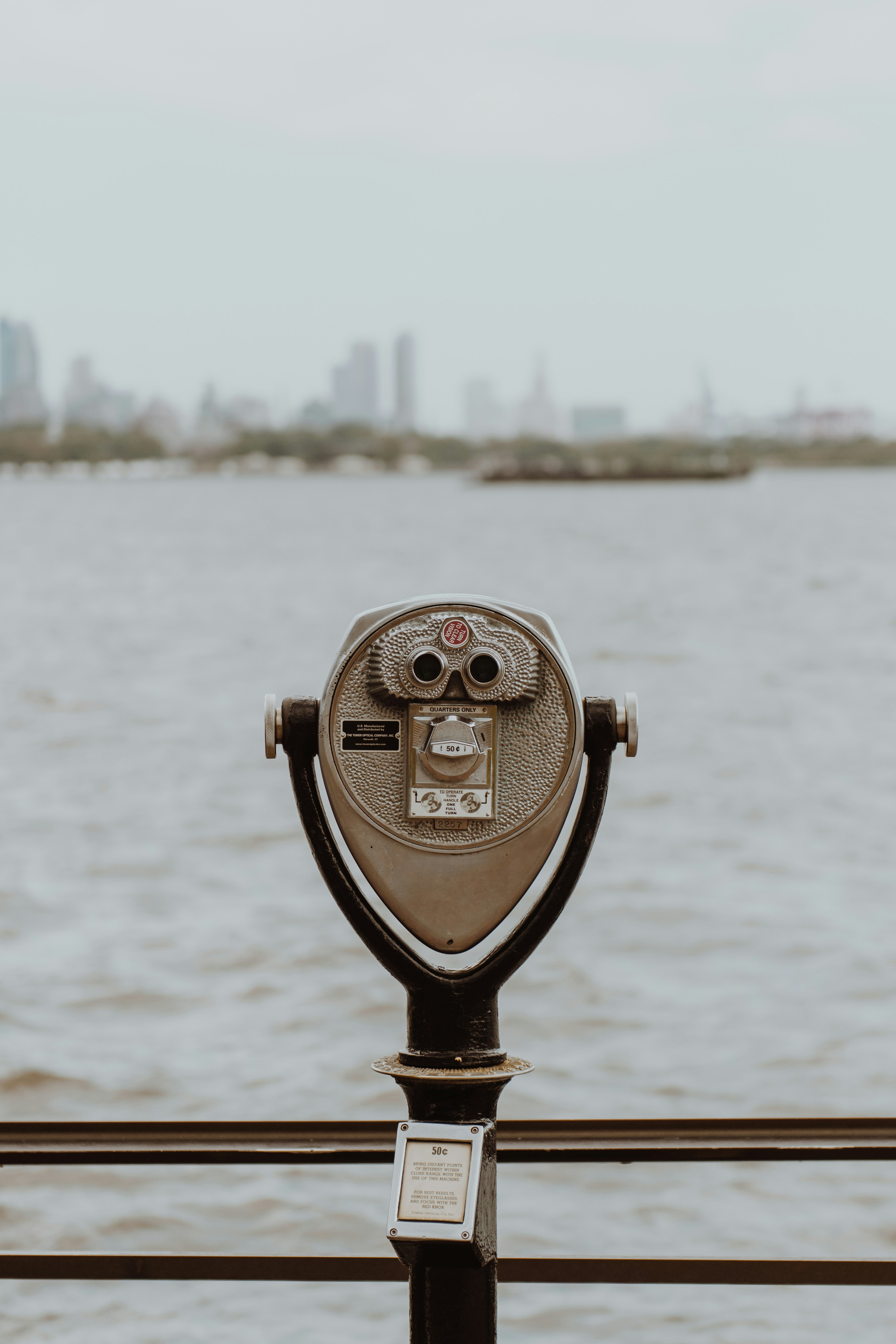 brown coin telescope facing skyscrapers across lake