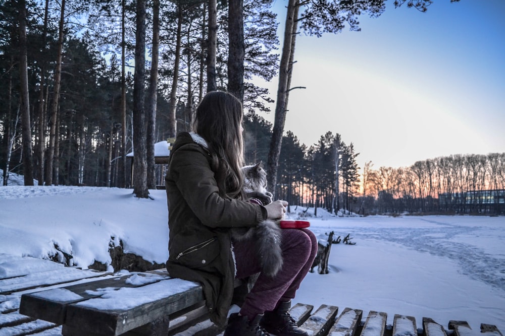 woman sitting on bench while carrying cat