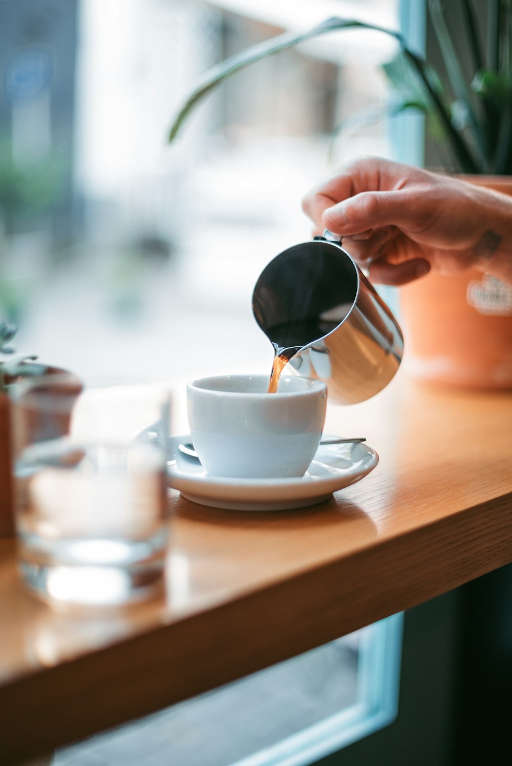 person pouring tea on white teacup