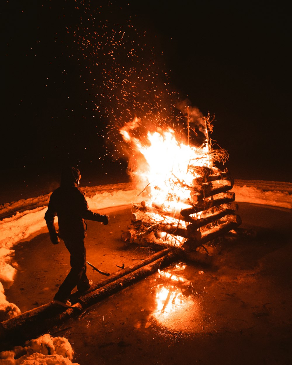 man standing near burning pile of wood