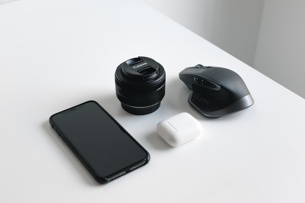 黒いスマートフォン、デジタル一眼レフカメラレンズ。とワイヤレスコンピュータマウス