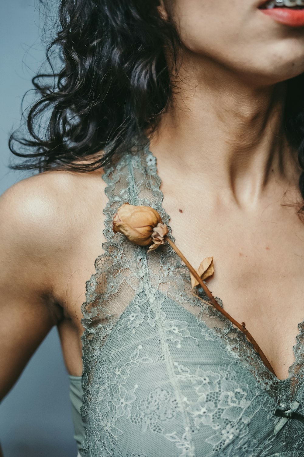 woman in grey lace top with brown withered rose