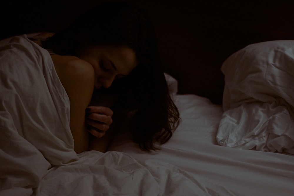 woman lying on white bed comforter