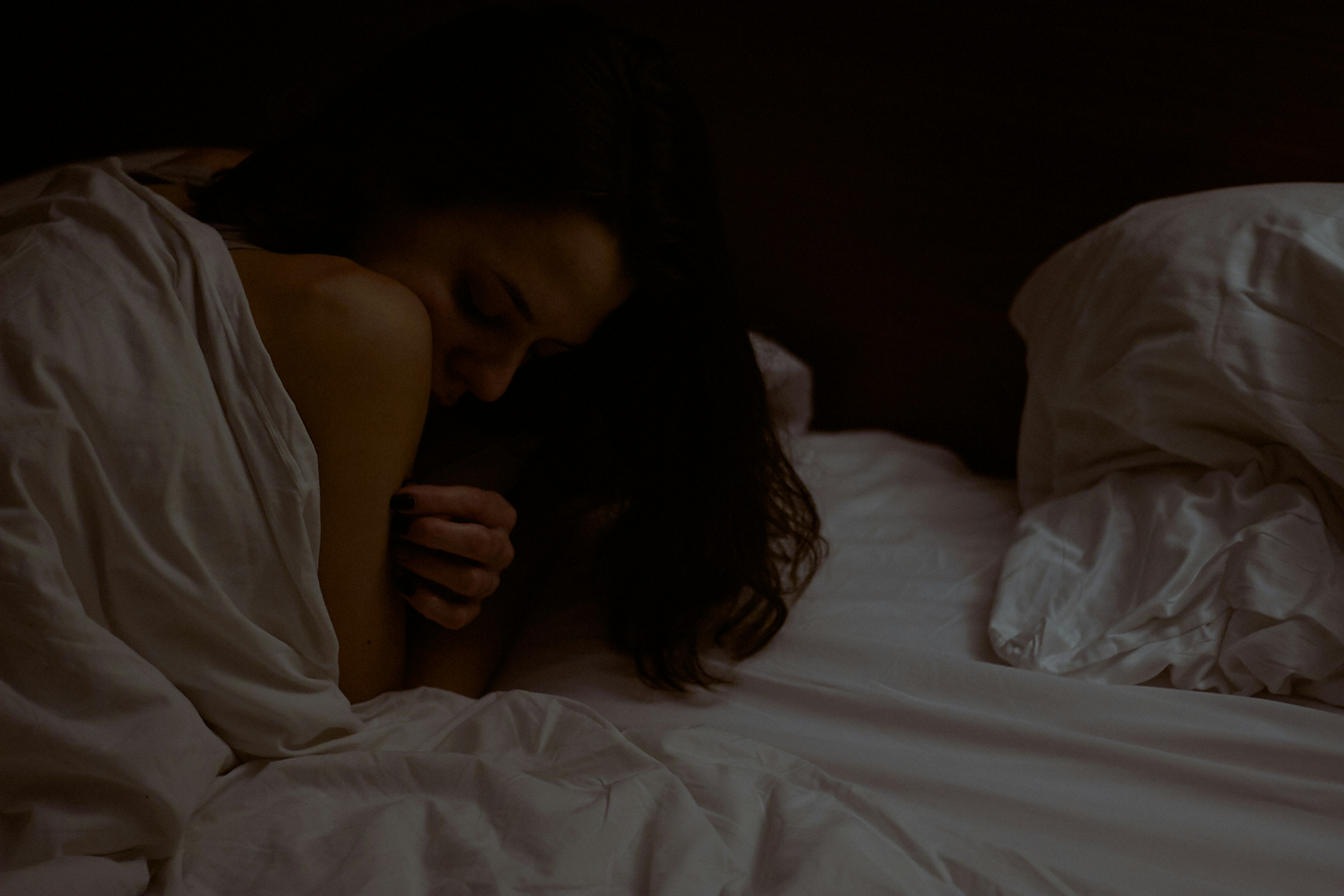 woman lying on white bed comforter