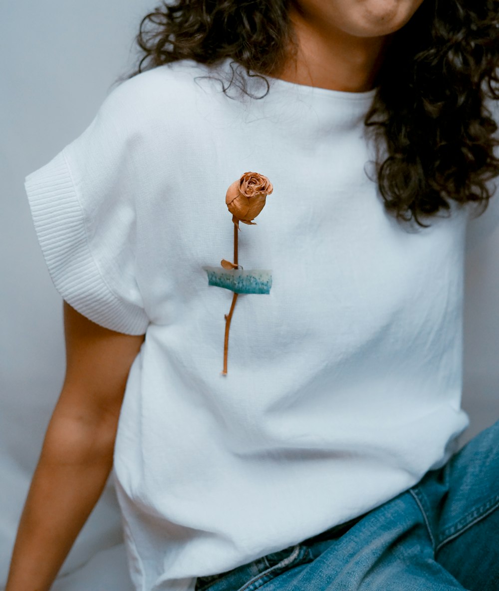 woman wearing white shirt with brown flower on her shirt