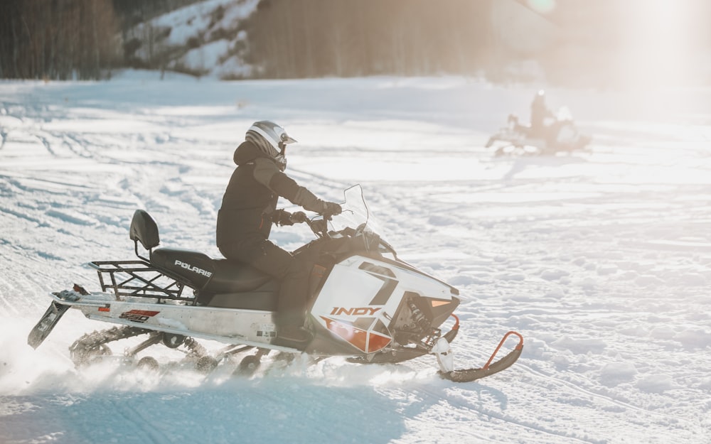 Two people on snowmobiles on snowy day