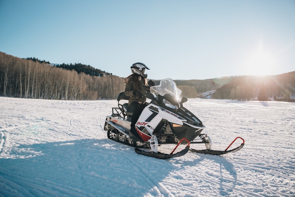 Persona que viaja en moto de nieve blanca y negra durante el día