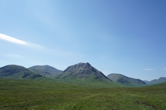 A quiet lot nestled among soft green hills with a clear sky and distant mountain peaks.