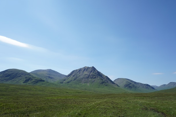 A quiet lot nestled among soft green hills with a clear sky and distant mountain peaks.