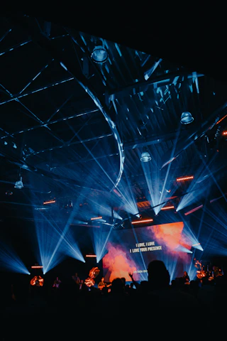 A dynamic, neon-lit concert stage with a crowd glowing under purple and blue lights, capturing the thrill of a live event at night.