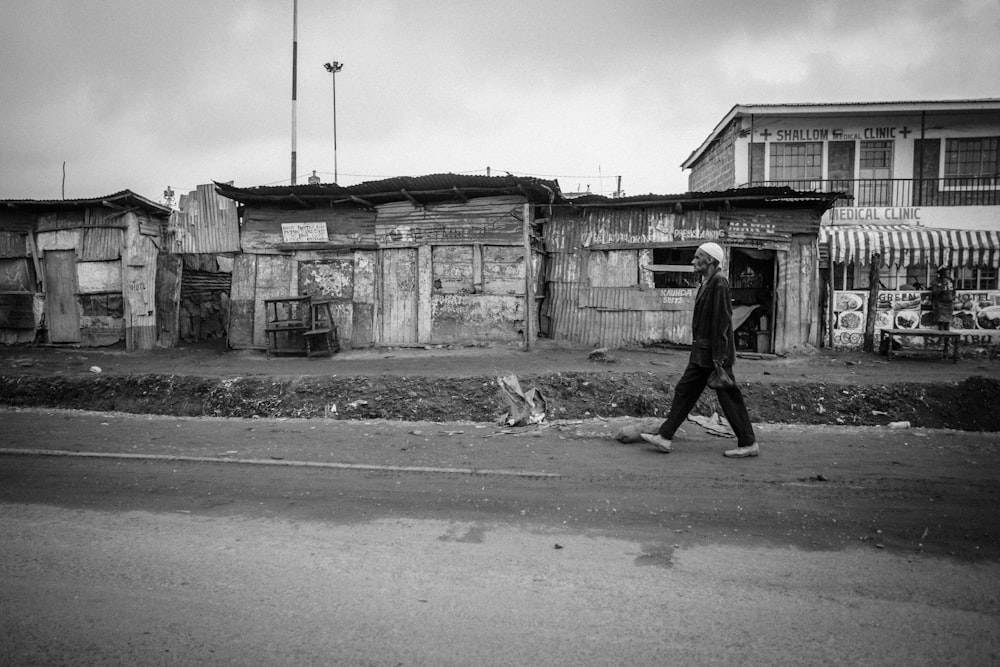 Foto en escala de grises de un hombre caminando por la carretera durante el día