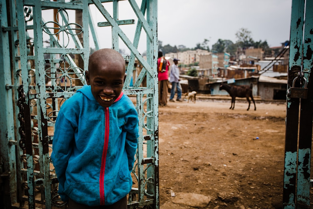 boy smiling leaning beside gate