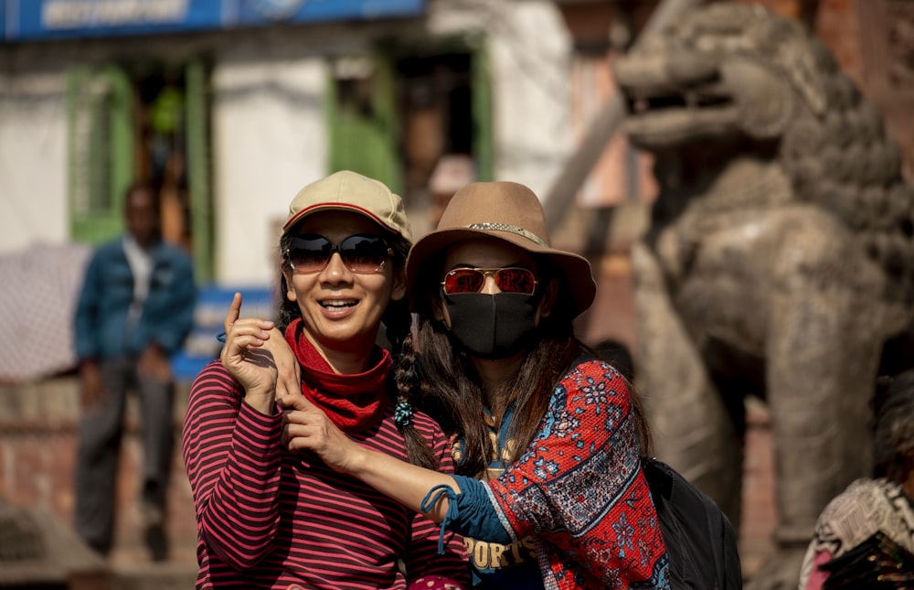 woman hugging woman while pointing and smiling during daytime