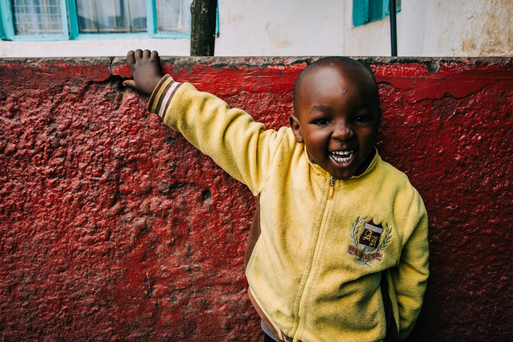 boy smiling raising right hand onto wall