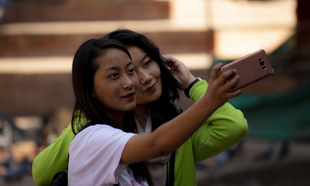 Première femme en chemise blanche tenant un smartphone à côté d’une deuxième femme souriante