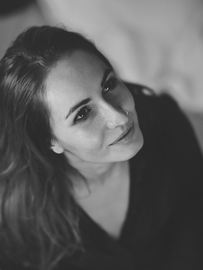 A monochrome portrait of a woman with soft light highlighting her serene expression against a dark background.