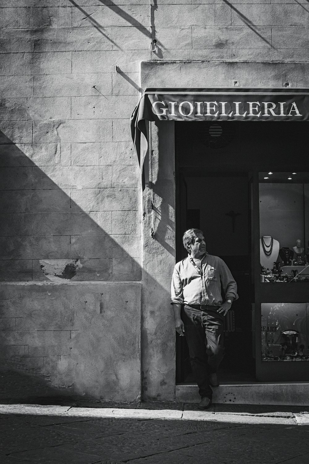 grayscale photography of man leaning on wall