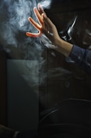 close-up of hands reaching through textured smoke with neon accents