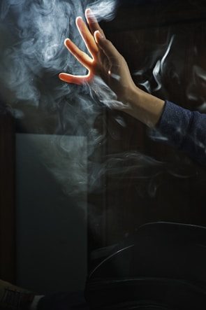 close-up of hands reaching through textured smoke with neon accents