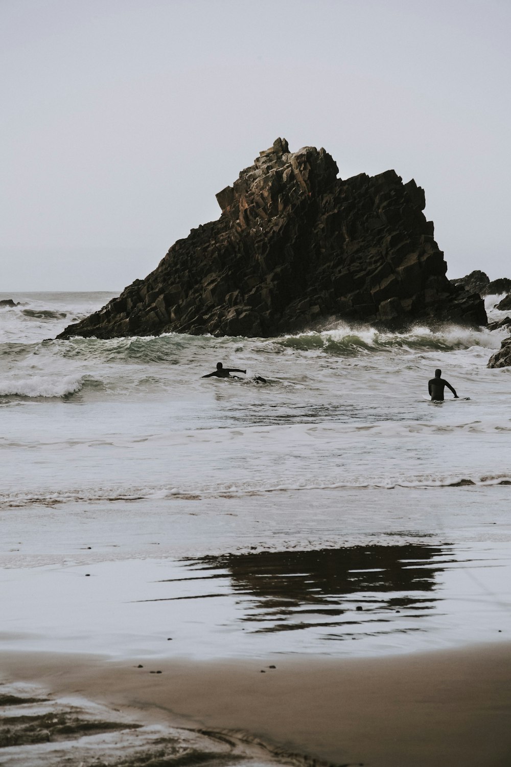 surfers on water near rock formation