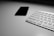 Hands typing on a smartphone with a sleek, minimalist desk setup in soft natural light.