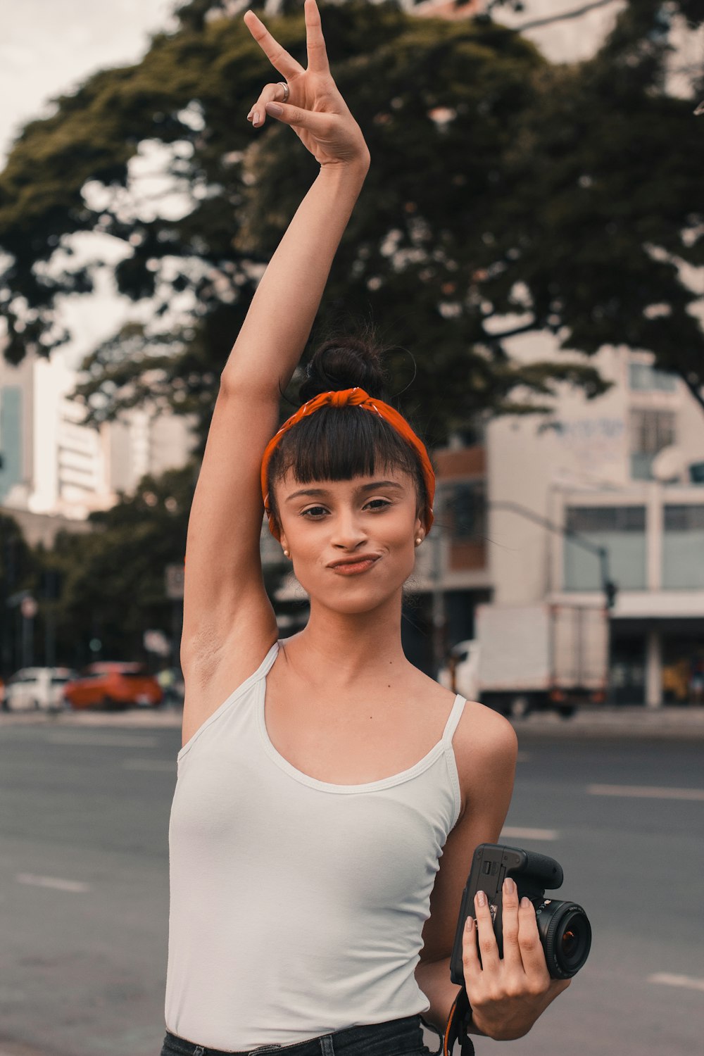 woman wearing white tank top holding out peace sign during daytime